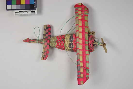 Hearst Museum object 3 of 4 titled Toy airplane, accession number 3-29240, described as Toy airplane, palm leaf in wickerweave; red, green and black; poor condition; L 20 cm.