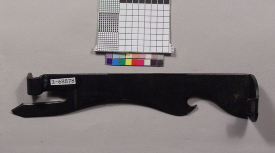Hearst Museum object titled Can opener, accession number 2-68878, described as Can opener/caplifter/jar lid remover combination; blued steel bar die stamped and formed into jar lid remover at one end, bottle cap opener near center and can opener at opposite end, one piece.  Kitchen tool.
