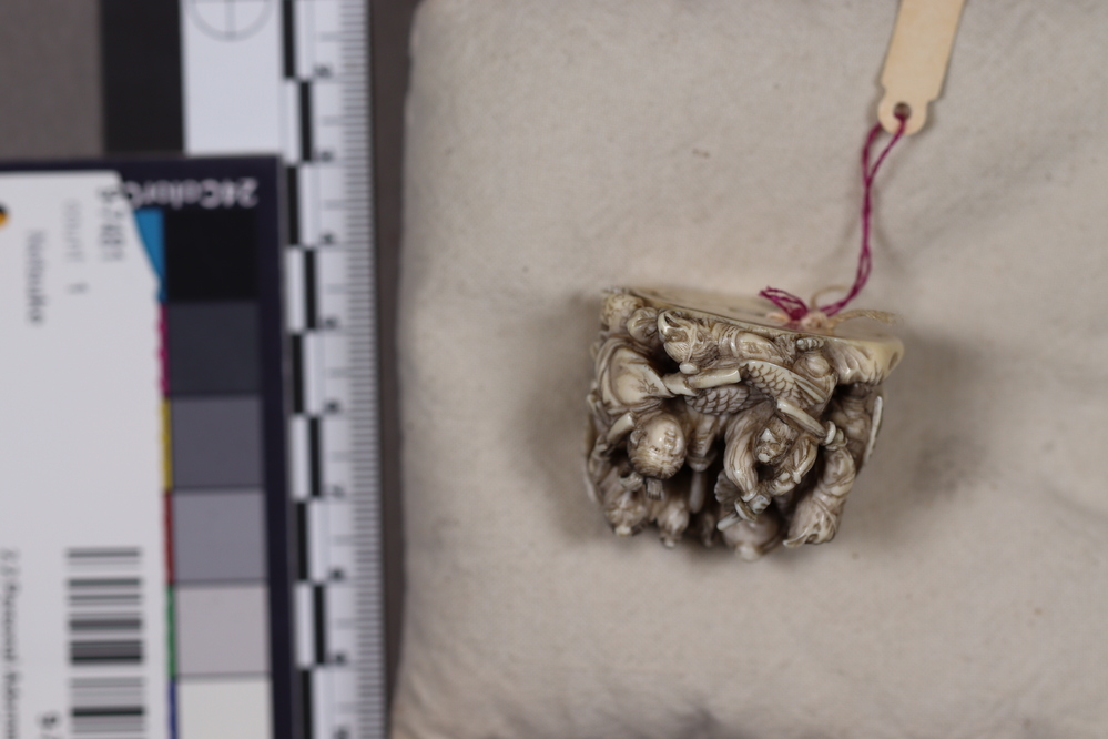 Hearst Museum object 4 of 6 titled Netsuke, accession number 9-7492, described as Netsuke: crowd of beasts with beaks (Tengu) of birds and wings. Principal figure, wearing armor, helmet and club, is female.