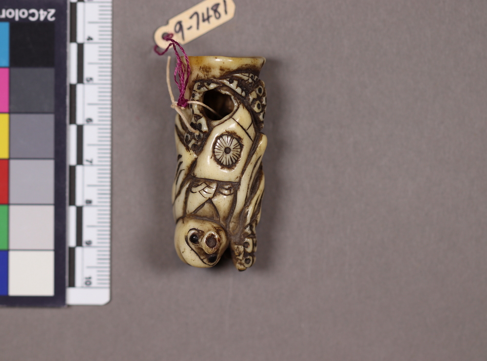 Hearst Museum object titled Netsuke, accession number 9-7481, described as Netsuke: figure, probably an octopus, wearing robe. Obsidian eyes. tentacles carved with holes.