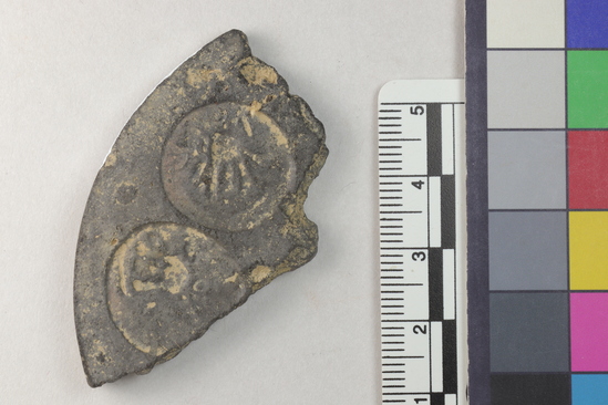 Hearst Museum object titled Coin mold fragment, accession number 9-22746, described as fragment; ceramic coin mould.  round with multiple moulds on each side (1 complete and 2 partial (recto); 1 complete and 2 partial (verso)).  mould depressions are 1.8 to 2.0 cm in diameter and decorated.  both sides appear  shallow and worn.  1 drain channel is present on the verso.