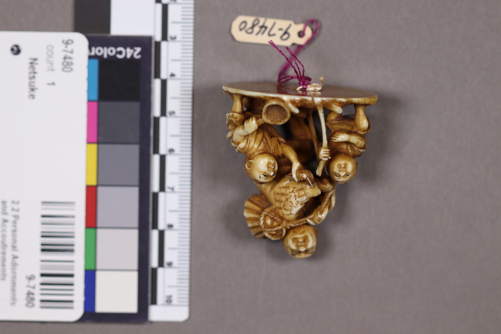 Hearst Museum object titled Netsuke, accession number 9-7480, described as Netsuke: man standing, with basket over left shoulder. Two children beside him; one holds staff, the other a basket.