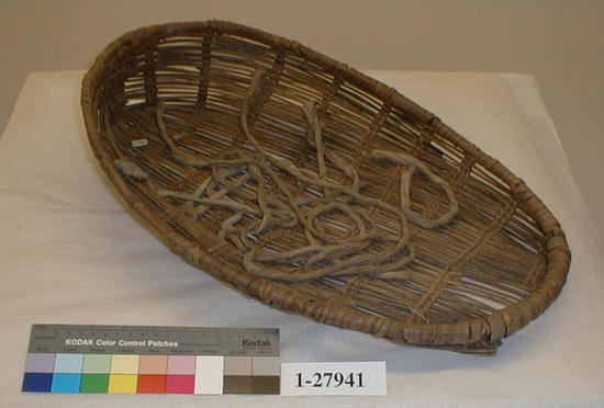 Hearst Museum object titled Cradle basket, accession number 1-27941, described as Fragile. Dirty and worn from use. Oval shape. Twined openwork. Groups of 2 rows slanted opposite directions. Hoop rim of shoots sewn together. Ties of white cotton fabric.