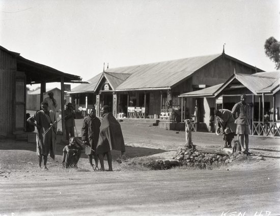 Hearst Museum object titled Black and white negative, accession number 15-32295, described as 4" x 5" Negative. Masai, Lumbwa, and Kamasia peoples represented. Hoefler stopped for supplies at a trading post in Eldama Ravine.  Hoefler's original description: "Trading Post, Eldama Ravine. The dukas (stores) are run by Hindus who have invaded every likely place with the white man's goods. The natives in the photo represents three tribes: Masai, Lumbwa, Kamasia.