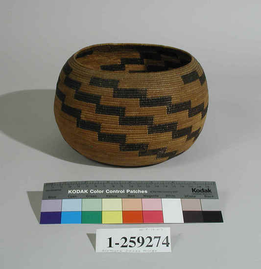 Hearst Museum object titled Basket, accession number 1-259274, described as Tightly coiled round open basket with black zig-zag pattern.