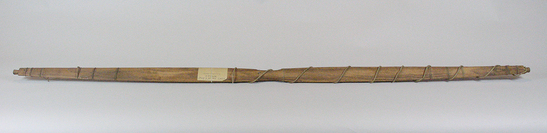 Hearst Museum object titled Bow, accession number 2-6358, described as Wooden shaft, center grip narrowed. Full length sinew cable backing broken towards ends, attached at either side of grip and two sets of four wrappings near ends. Twisted sinew bowstring. wood, carved; front surface reinforced with a small bundle of sinew string, which is partly damaged; strong bow string of twisted sinew; section of wood is convex on front and flat on backside. Alutiiq name: qitguyaq.