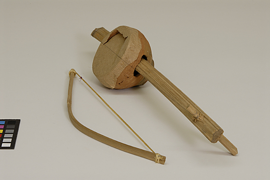 Hearst Museum object titled Musical instrument, accession number 9-10954a,b, described as toy stringed musical instrument width bow; clay, bamboo, paper, wire, wood; instrument:  39.5 cm length;  9.5 cm width;  bow:  30.5 cm length