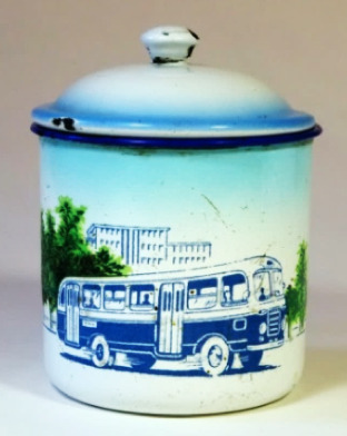 Hearst Museum object titled Mug with lid, accession number 9-23953a,b, described as Enamel mug with lid. The white ground is decorated with a transferred decal of a blue bus rushing forward in a street lined with trees. The top of a modern building appears in the background. The top of the mug and the edge of the lid are sprayed with sky blue pigment. A blue bowstring decorates the rim. RMB 70