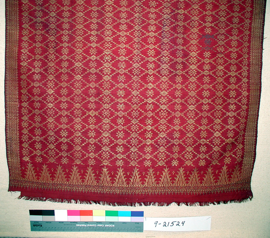 Hearst Museum object titled Shawl, accession number 9-21524, described as Shawl:  L= 223 , W=75.5 ; Dark red silk  w/ gold, diamond grid pattern and 8-pointed gold stars or flowers in diamond centers.  Stylized tree motifs & geometric patterns in horizontal band at end.  Geometric pattern borders on both sides of center field.  Fringe 1.5 cm.