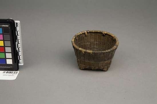 Hearst Museum object titled Basket, accession number 10-1311, described as Wicker basket with checker bottom of bamboo; dark brown; square bottom; round top; 4 1/4 2dia. x 2 5/8”hi.