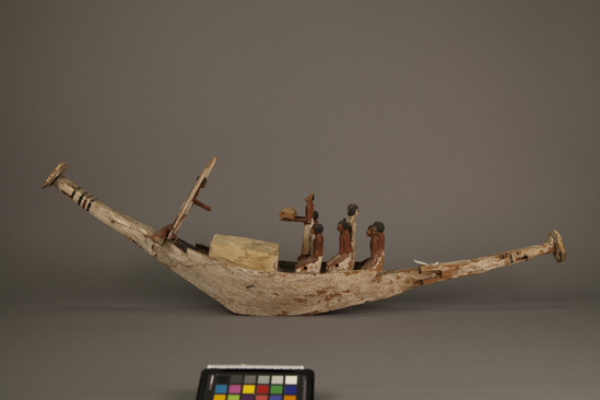 Hearst Museum object titled Model boat, accession number 6-17156a-d, described as a) wooden model boat found in tomb, decorated canopy with coffin beneath. b) standing pilot figure (detached). c-d) two oars. 11 small bags dust/fragment - samples saved during conservation treatment.