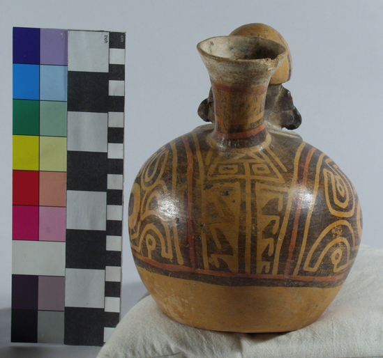 Hearst Museum object 12 of 13 titled Bottle, accession number 16-12114, described as Pottery bottle with flaring spout; effigy of a man with bag slung around neck; red and white slip and resist painted designs. Has been waxed