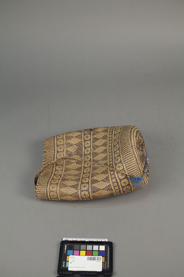 Hearst Museum object titled Bag, accession number 18-1267, described as Bag; twill plaited, of black and natural rattan. Geometric pattern. Straps alternated black and white geometric pattern. For use by men when traveling beyond the village. In it are usually carried rive and tobacco, a spare waist cloth, a sleeping mat, sometimes a palm leaf rain mat, a roll of dried banana leaves for making cigarettes, and perhaps a cap for wearing in the house. The Punan women make them and trade them to several neighboring tribes who greatly prize them. Length 58 cm. Bag length 30 cm. Bag width 23 cm.