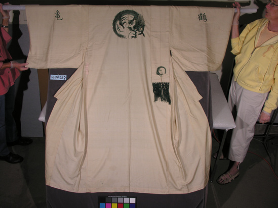 Hearst Museum object titled Robe, accession number 9-17958a,b, described as Kimono:  beige silk plainweave w/ 3-toed dragon medallion in center back; "green" characters on sleeves; machine sewn, matching belt w/ green silk fringe.  Soiled at hem.  Plainweave silk, machine sewn.  Kimono for export:  embroidery relatively crude; "green" character on sleeve very old-fashioned form.  Label in the back: "Made in Japan". A) 159 cmm L.  B) 241 cm L.