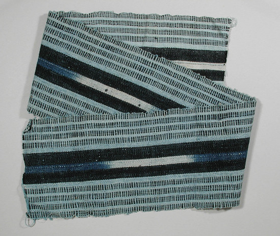 Hearst Museum object titled Textile fragment, accession number 5-11311, described as textile sample (section of narrow band weaving): light blue ground, center panel ikat: indigo and white flanked by black outer panels, light blue solid alternating with black and light blue pin stripes showing horizontally.