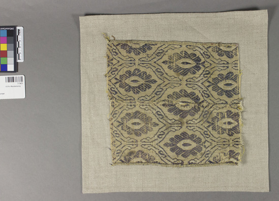 Hearst Museum object 1 of 2 titled Textile sample, accession number 7-7471, described as Description: Framed piece. Silk, plain weave, brocaded. Blue and light brown. 7 inches x 7 1/2 inches. Pattern incomplete.