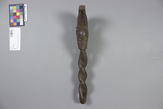 Hearst Museum object titled Gong stick, accession number 5-3214, described as Carved wooden gong stick. Handle carved in twisted fashiion with head in form of prong-horned bovine. L = 11.75”.