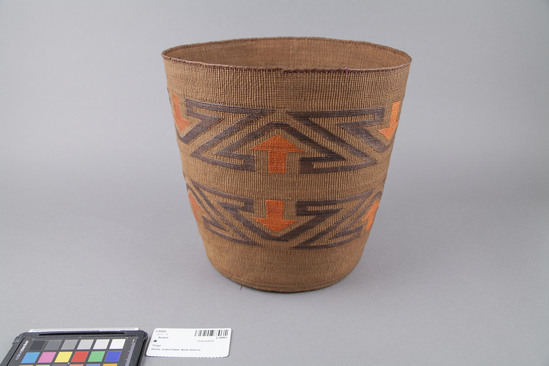 Hearst Museum object 2 of 3 titled Basket, accession number 2-30993, described as Cylindrical, twined spruce root, exterior false embroidery of grass stems dyed dark brown and orange: "Z" and arrow designs; interior green, brown and black bands of dyed spruce roots. Cardboard strip sewn to base.