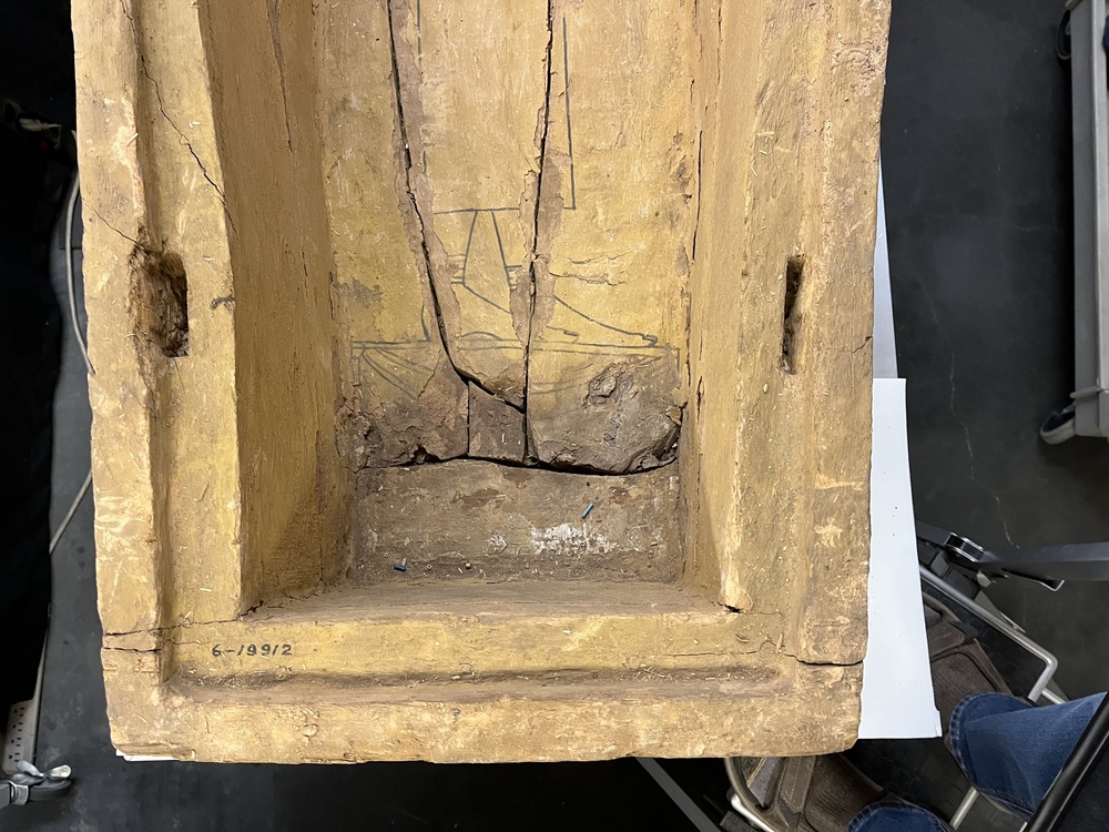 Hearst Museum object 90 of 167 titled Coffin, accession number 6-19912, described as Wooden anthropoid coffin. Inscription running down center of lid. Determined by Kea Johnston to probably be the outer coffin of Iwefaa (6-19928, 12-11039). According to Kea Johnston, "This coffin belonged to a man named Iwefaa, whose name is inserted in the middle of the spells written in the two columns on the front. This coffin is likely the outer coffin for PAHMA 6-19928 based on the similarity of the owner's name, unusual costume, and the paleography of the inscription. Both coffins were purchased on the antiquities market by George Reisner for Phoebe A Hearst. However, stylistically, they are very similar to a set of coffins known to have come from the site of Akhmim, which was excavated in the 1880s by Gaston Maspero, and which has heavily looted for the antiquities market during this decade." "The pectoral vignette between the text and the collar shows the deceased standing before squatting baboon and is the source of our logo. The hieroglyph for 'sky' is above their heads, and the side borders are formed by a pyramid and the symbol for the West.