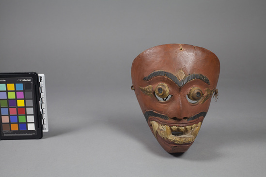 Hearst Museum object titled Mask, accession number 18-1194, described as Mask, wood, carved and painted; jutting lower jaw and fang-like teeth; tan, gold, black and red. Used in dance. 18.0 cm.