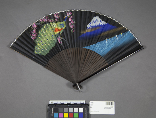 Hearst Museum object titled Fan, accession number 9-17606, described as Fan: folding, black silk leaf painted w/ peacock, Mt. Fuji & Inland Sea; silver paper binding; black stained bamboo sticks, painted guards; brass loop.  Stamped "Made in Occupied Japan;".  Japan unsp.  Ca. 1940-1945.  45.4 cm by 25.3 cm.