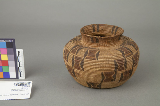 Hearst Museum object 2 of 2 titled Basket, accession number 1-235263, described as Money basket"; small-necked jar-shaped coiled basket.  Design is diagonal blocks each with red hourglass shaped center and black edges; stained with blue ink.