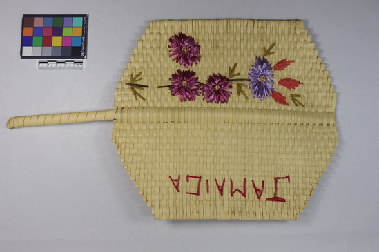 Hearst Museum object 4 of 5 titled Woven mat, accession number 3-28677, described as Woven mat with handle; floral pattern and "Jamaica" embroidered in colored straw