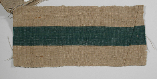 Hearst Museum object titled Textile fragment, accession number 5-11029, described as Textile sample (section of narrow band weaving). Brown beige ground with central 3.2 cm green stripe. Narrow .4 cm blue green stripe in left side of green stripe.