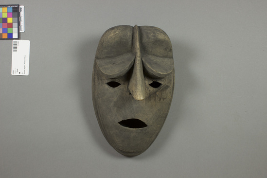 Hearst Museum object titled Mask, accession number 5-6353, described as Wooden, male, Ijaw mask, Bomadi light colored wood, gray on outer surface; long sharply pointed nose extends to top of head in narrow ridge; semi-circular shelf-like eye lids or brow ridges protrude above pierced eyes. L = 25.0 cm, W = 16.0 cm. Collected ca. 1957 by John Davies.