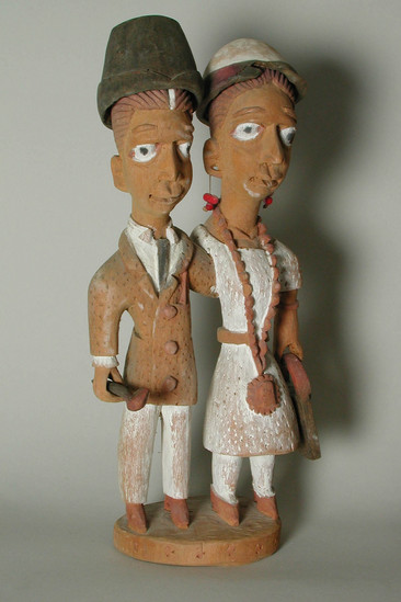 Hearst Museum object titled Figures, accession number 5-16236a-e, described as Caricature figures of a British married couple; woman in white dress with pendant necklace and red dangle earrings; man in white pants, white shirt, a sport coat and tie. Both have hats; man has cane, woman has purse. a) figures, b) man's hat, c) woman's hat, d) purse, e) cane. Condition - thumb of woman's left hand chipped