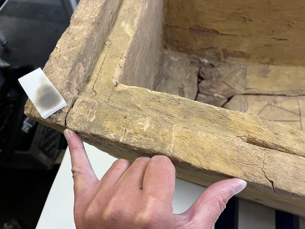 Hearst Museum object 67 of 167 titled Coffin, accession number 6-19912, described as Wooden anthropoid coffin. Inscription running down center of lid. Determined by Kea Johnston to probably be the outer coffin of Iwefaa (6-19928, 12-11039). According to Kea Johnston, "This coffin belonged to a man named Iwefaa, whose name is inserted in the middle of the spells written in the two columns on the front. This coffin is likely the outer coffin for PAHMA 6-19928 based on the similarity of the owner's name, unusual costume, and the paleography of the inscription. Both coffins were purchased on the antiquities market by George Reisner for Phoebe A Hearst. However, stylistically, they are very similar to a set of coffins known to have come from the site of Akhmim, which was excavated in the 1880s by Gaston Maspero, and which has heavily looted for the antiquities market during this decade." "The pectoral vignette between the text and the collar shows the deceased standing before squatting baboon and is the source of our logo. The hieroglyph for 'sky' is above their heads, and the side borders are formed by a pyramid and the symbol for the West.