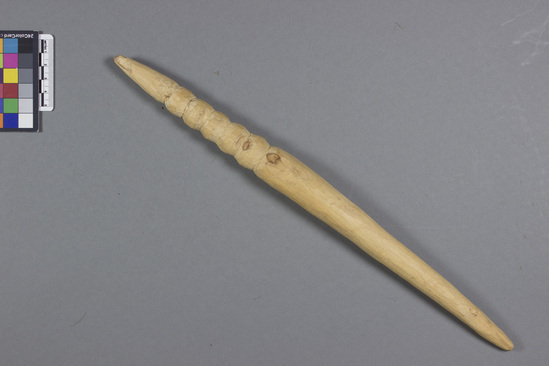 Hearst Museum object titled Stick, accession number 5-17036, described as Natural wood stick, hand carved with a point on each end, and 6 grooves carved into the stick along 13.0cm of one end.  1962