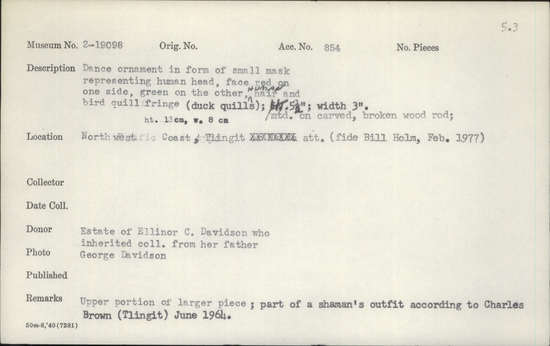 Documentation associated with Hearst Museum object titled Headdress ornament, accession number 2-19098, described as In form of small mask representing human head, face red on one side, green on the other, human hair and duck quill fringe. Mounted on carved, broken wood rod. Upper portion of larger piece.
