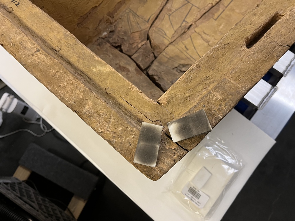 Hearst Museum object 9 of 167 titled Coffin, accession number 6-19912, described as Wooden anthropoid coffin. Inscription running down center of lid. Determined by Kea Johnston to probably be the outer coffin of Iwefaa (6-19928, 12-11039). According to Kea Johnston, "This coffin belonged to a man named Iwefaa, whose name is inserted in the middle of the spells written in the two columns on the front. This coffin is likely the outer coffin for PAHMA 6-19928 based on the similarity of the owner's name, unusual costume, and the paleography of the inscription. Both coffins were purchased on the antiquities market by George Reisner for Phoebe A Hearst. However, stylistically, they are very similar to a set of coffins known to have come from the site of Akhmim, which was excavated in the 1880s by Gaston Maspero, and which has heavily looted for the antiquities market during this decade." "The pectoral vignette between the text and the collar shows the deceased standing before squatting baboon and is the source of our logo. The hieroglyph for 'sky' is above their heads, and the side borders are formed by a pyramid and the symbol for the West.