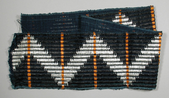 Hearst Museum object titled Textile fragment, accession number 5-11348, described as textile sample (section of narrow band weaving): black and white silk or rayon brocade in a zig-zag pattern with crossing orange rayon or silk brocade stripes.