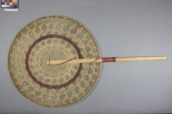 Hearst Museum object titled Fan, accession number 11-39726, described as Fan, pandanus in looped coiling; round 4 courses of red hibiscus, some hibiscus on handle; handle breadfruit wood (?); length 68.5 cm. Diameter 39.5 cm