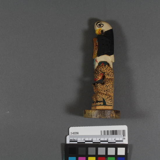 Hearst Museum object 2 of 3 titled Totem pole model, accession number 2-45356, described as Carved and painted wood totem pole model; top half is bird with recurved beak, black and white exterior pigmentation, also red, yellow, and light blue pigment used; fish below; bottom half is a seated bear. Written in back in ink is: "Eli T (? ) Metlakatla Alaska".