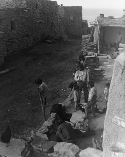 Hearst Museum object titled Black-and-white negative, accession number 15-257, described as Looking down on first story rooftop; three men and five children on roof; man butchering two sheep; entrails placed in yucca leaf basket; chicken on left foreground.