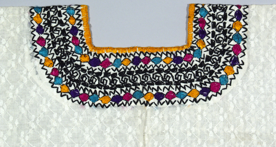 Hearst Museum object 3 of 3 titled Huipil, accession number 3-28126, described as [ cat card DESCRIPTION: Blouse Materials: Cotton, silk Technique: Plain weave, embroidered Colors: White ground varicolored designs Dimensions: 14 x 28" Remarks:  Bead, wave motives. Factory woven. See Fig. 98a Textiles of Highland Guatemala, LMO    ]