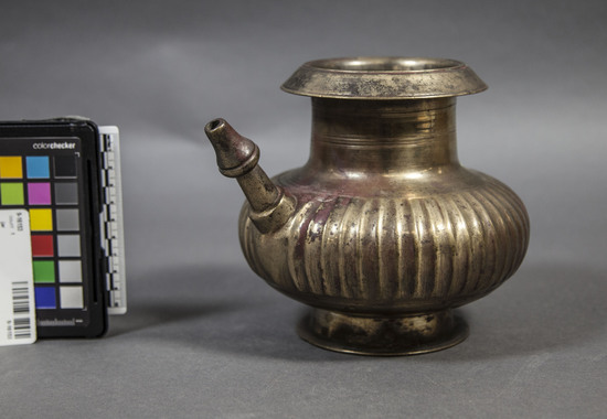 Hearst Museum object titled Jar, accession number 9-16153, described as Water jar (lota), made of brass with vertical ridges on lower portion. Muslin type with straight spout & flange. 16cm height, 8 cm width at mouth.