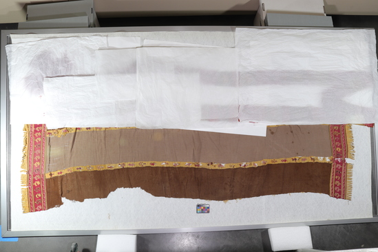 Hearst Museum object titled Textile, accession number 16-14944, described as Textile: brown and beige alternating strips forming a large rectangular cloth. Borders and bands between strips have bird designs. Tab fringe on each end 100 by 202 cm