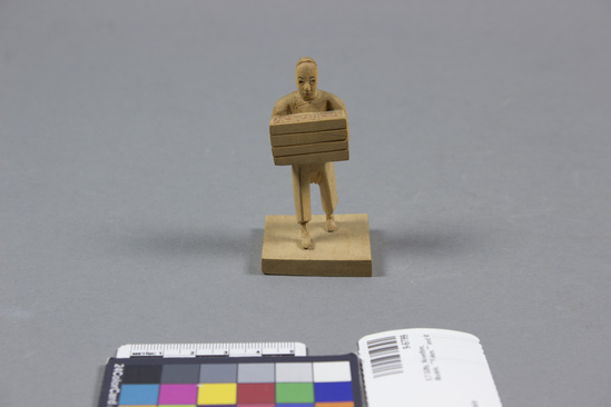 Hearst Museum object titled Figurine, accession number 9-6799, described as Wooden model: man carrying box; height 3 inches.