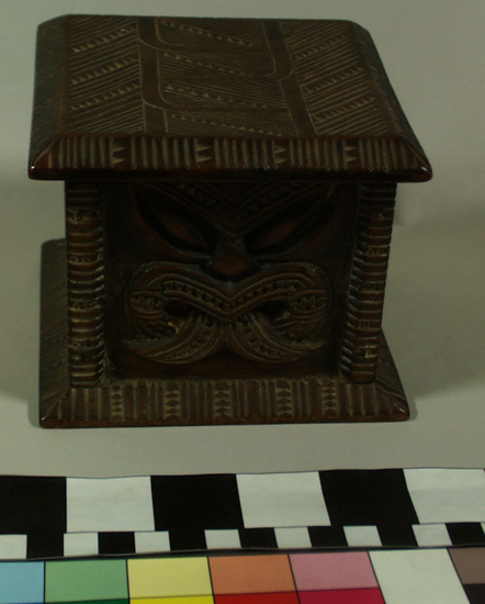 Hearst Museum object titled Carved wooden box, accession number 11-42799a,b, described as Box and lid, wood, carved in relief, geometric pattern on lid and two sides of box, facial image carved on other two sides of box; tan and brown.