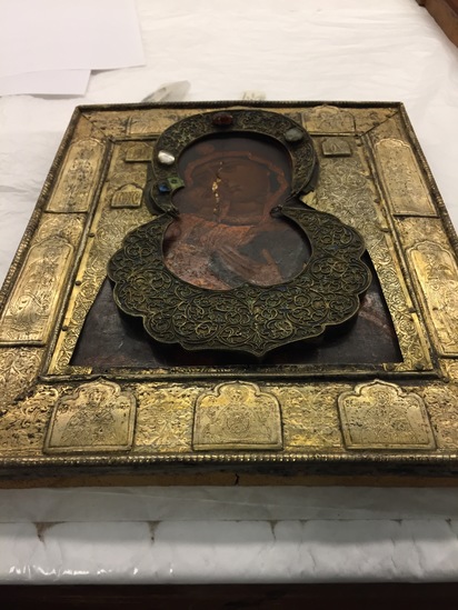 Hearst Museum object 5 of 49 titled Icon, accession number 7-3541, described as Icon of “Our lady of Vladmir”; Virgin and Child in tempera and gesso on wood; gilded silver basma; cloisonne halo with cloisonne collar pendant; halo has glass and amber (?) ornamentation; Virgin’s face damaged; height 30.2 cm, width 26 cm.