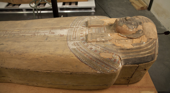 Hearst Museum object 18 of 167 titled Coffin, accession number 6-19912, described as Wooden anthropoid coffin. Inscription running down center of lid. Determined by Kea Johnston to probably be the outer coffin of Iwefaa (6-19928, 12-11039). According to Kea Johnston, "This coffin belonged to a man named Iwefaa, whose name is inserted in the middle of the spells written in the two columns on the front. This coffin is likely the outer coffin for PAHMA 6-19928 based on the similarity of the owner's name, unusual costume, and the paleography of the inscription. Both coffins were purchased on the antiquities market by George Reisner for Phoebe A Hearst. However, stylistically, they are very similar to a set of coffins known to have come from the site of Akhmim, which was excavated in the 1880s by Gaston Maspero, and which has heavily looted for the antiquities market during this decade." "The pectoral vignette between the text and the collar shows the deceased standing before squatting baboon and is the source of our logo. The hieroglyph for 'sky' is above their heads, and the side borders are formed by a pyramid and the symbol for the West.