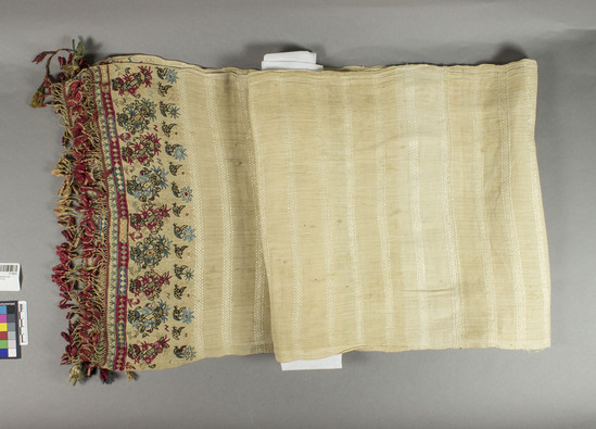 Hearst Museum object titled Bed hanging, accession number 9-15023, described as Towel?, bed hanging?  Line warp, silk weft, metal wrapped yarns, flat metal strips, silk embroidered.  Plain weave, embroidered, brocaded; fringes with tassels.  Natural ground, and varicolored designs.  Floral motives.  82 inches by 15 inches.