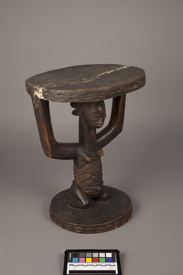 Hearst Museum object titled Stool (seating furniture), accession number 5-5288, described as dark stained stool with seat supported by kneeling woman with elaborate scarification on torso; wood; height 39.5 cm