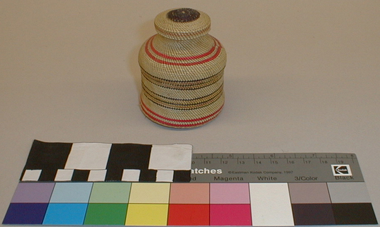 Hearst Museum object titled Inkwell, accession number 2-44860a,b, described as (a) Basketry covered inkwell; spiral lattice binding technique with fuchsia, black, yellow and red horizontal rows on straw-colored ground. (b) Cover.