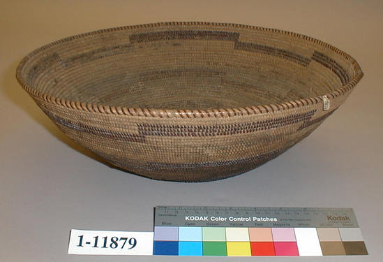 Hearst Museum object 1 of 2 titled Cooking basket, accession number 1-11879, described as Large flaring coiled basket.  Tag: "Yuki". Per Ralph Shanks:  Coiled flaring basket Yuki cooking bowl, with residue from food and wear from cooking.  The bottom 2/3rds of the exterior of the basket are blackened.  The basket has a twined start.  The coil foundation is two rods and splints of peeled shoots.  The wefts are peeled redbud with unpeeled redbud designs.  The design on the basket is three horizontal bands that drop down and go up at the same areas. There are no random rectangles. The rim is plain wrapped, with rim ticks.  The coil ending is cut off, with about three weft stiches missing.  The weft fag ends are primarily clipped or concealed.  The weft moving ends are primarily concealed.  The exterior has below 10% split stiches.  The interior of the basket has over 50% split stiches.  The basket has an exterior workface with a rightward work direction and a down to the right slant of weft twist.  The lack of random rectangles suggests some Wailaki influnce.