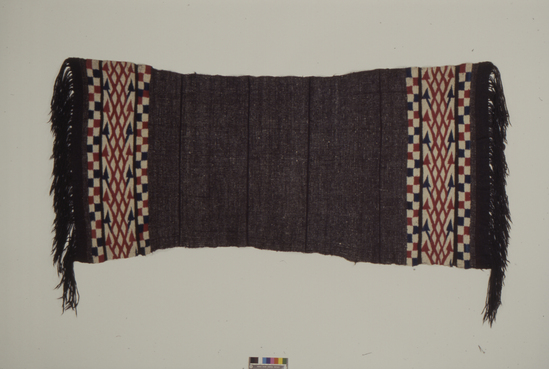 Hearst Museum object 1 of 2 titled Chamarro, accession number 3-12, described as Chamarro of native; wool; twill and tapestry weaves; brown, white, red, blue; long fringe; approximately 2 m long and 90 cm wide REMARKS: Ornamentation ancient